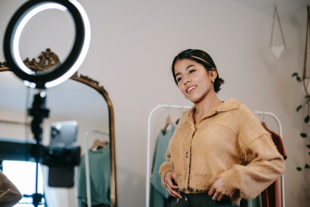 Un'influencer si sta riprendendo con una ring light mentre sponsorizza alcuni capi di moda