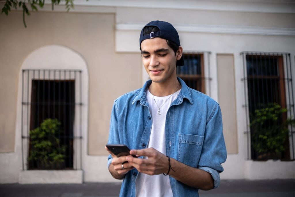 ragazzo con cappello che utilizza il suo smartphone