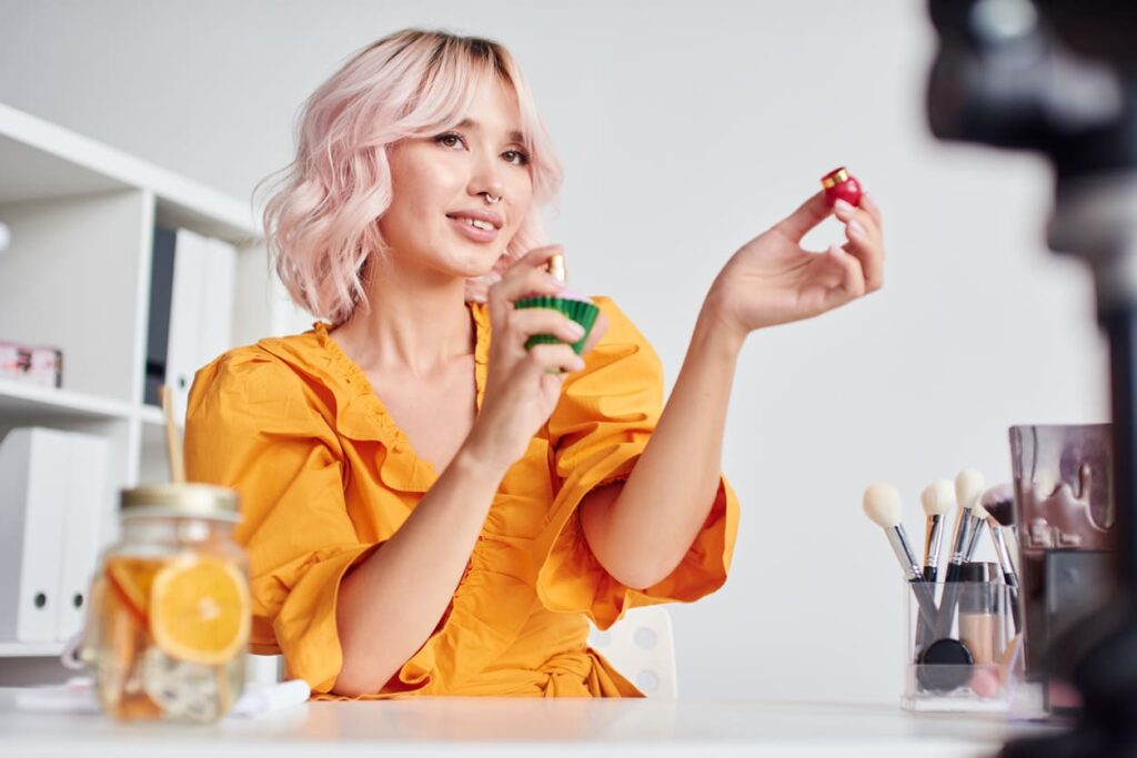 ragazza con i capelli rosa si spruzza il profumo sui polsi