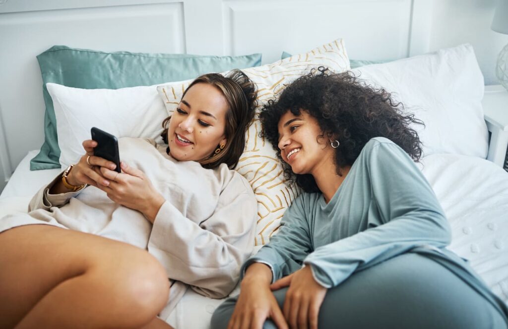 amiche sul letto che guardano il cellulare e ridono