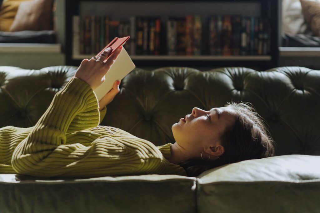 ragazza che legge un libro stesa sul divano