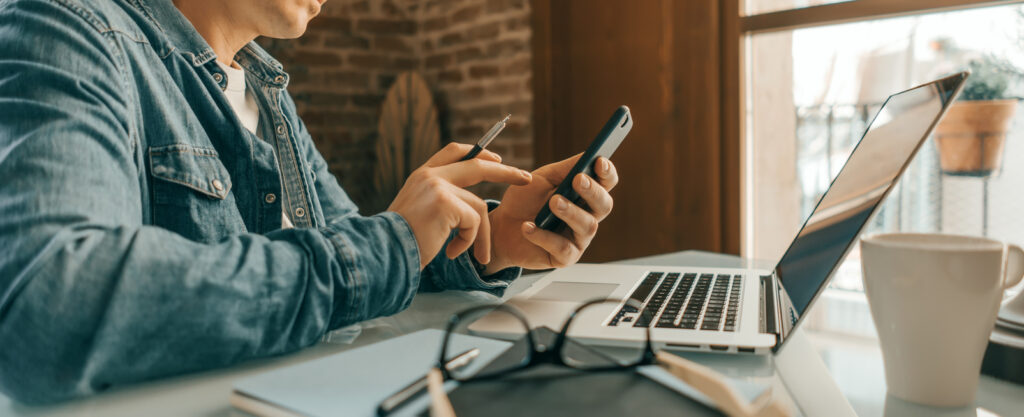 ragazzo che guarda il cellulare alla scrivania